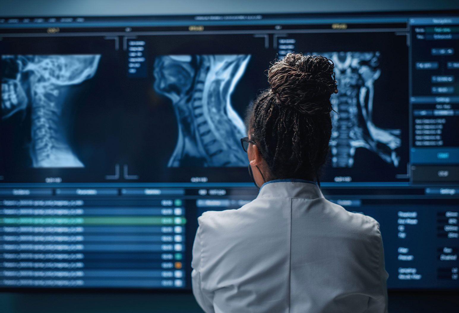 Medical Hospital Research Lab: Black Female Neuroscientist Looking at TV Screen, Analyzing Brain Scan MRI Images, Finding Treatment for Patient. Health Care Neurologist Curing People. Back View Zoom