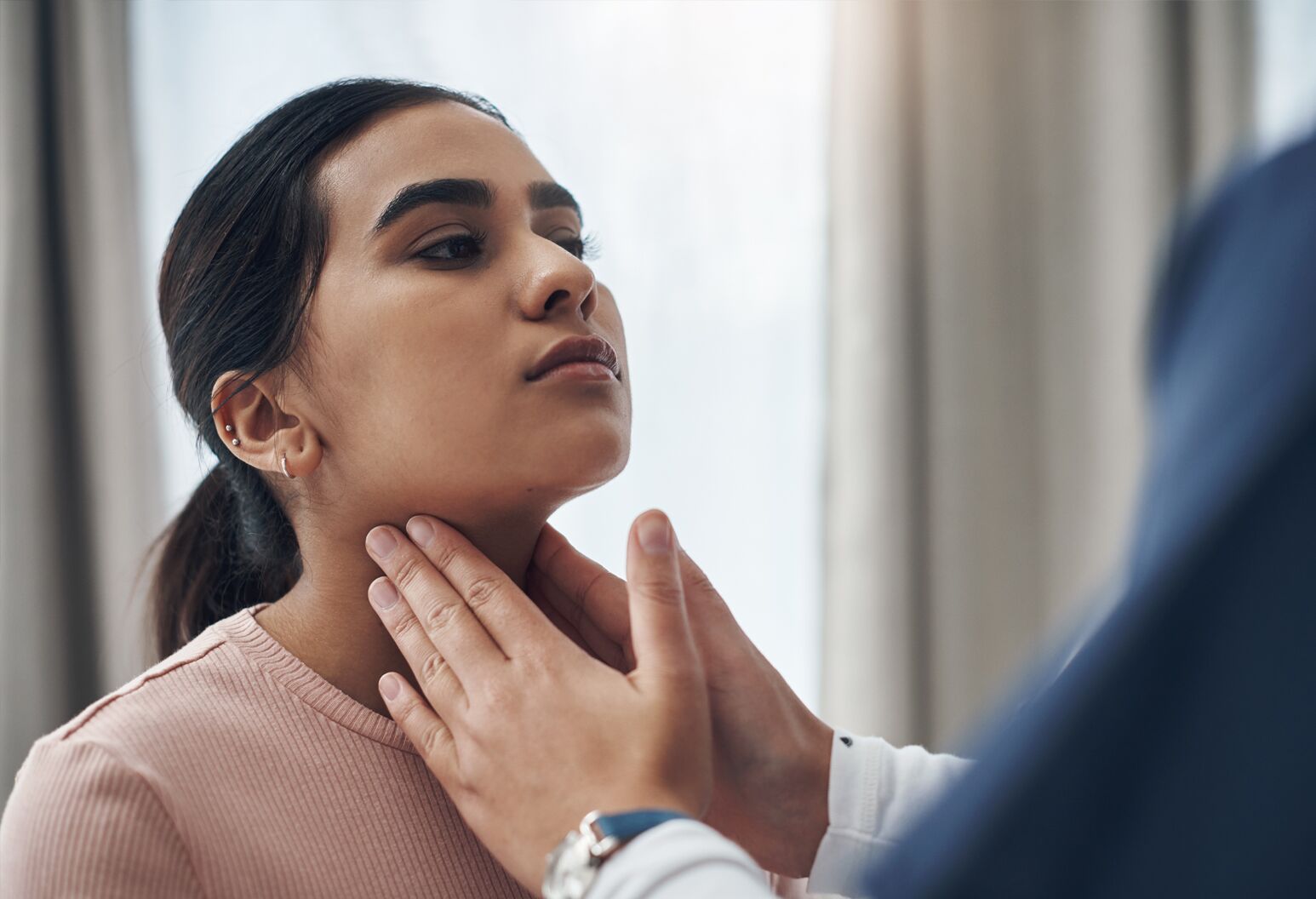 A doctor examining a womanâs neck.