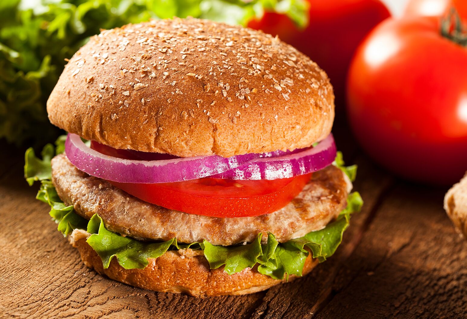 Turkey burger on a whole wheat bun with lettuce, tomato, and onion.