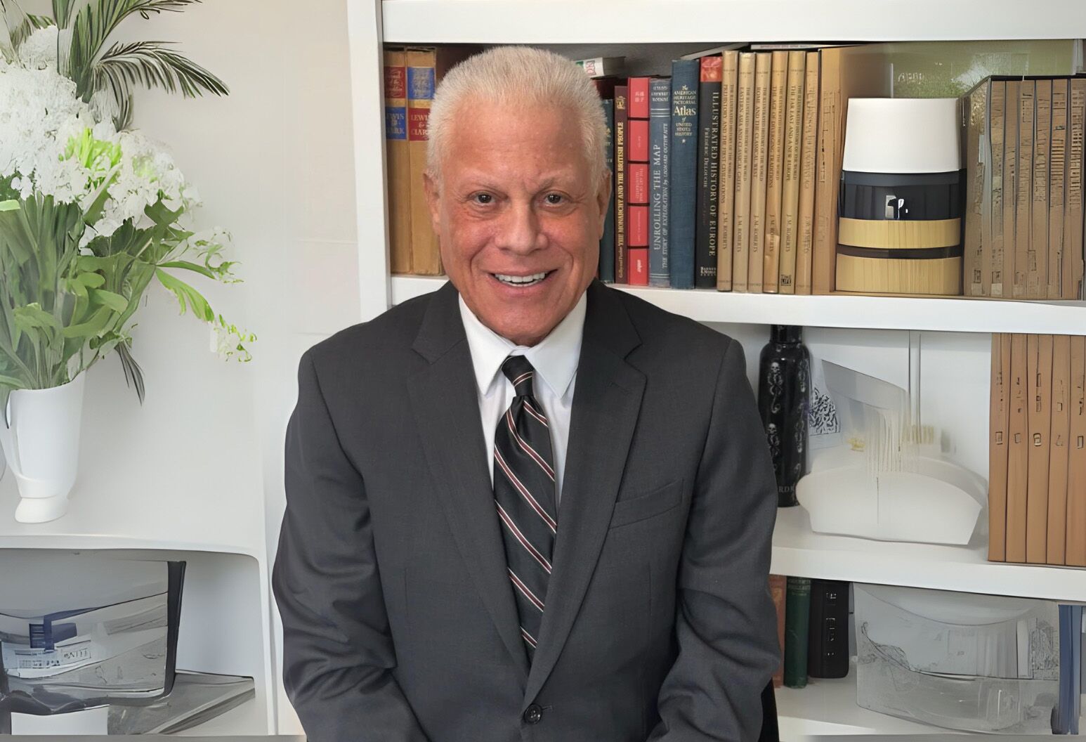 A man in a suit smiles in a modern-looking personal study.