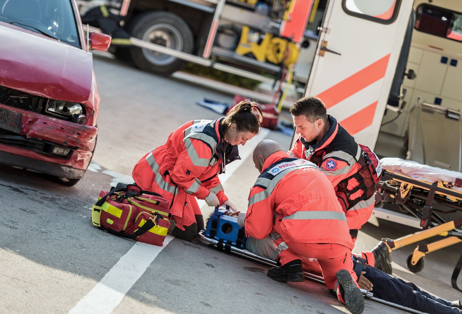 Emergency clinicians work on an individual after a car accident.
