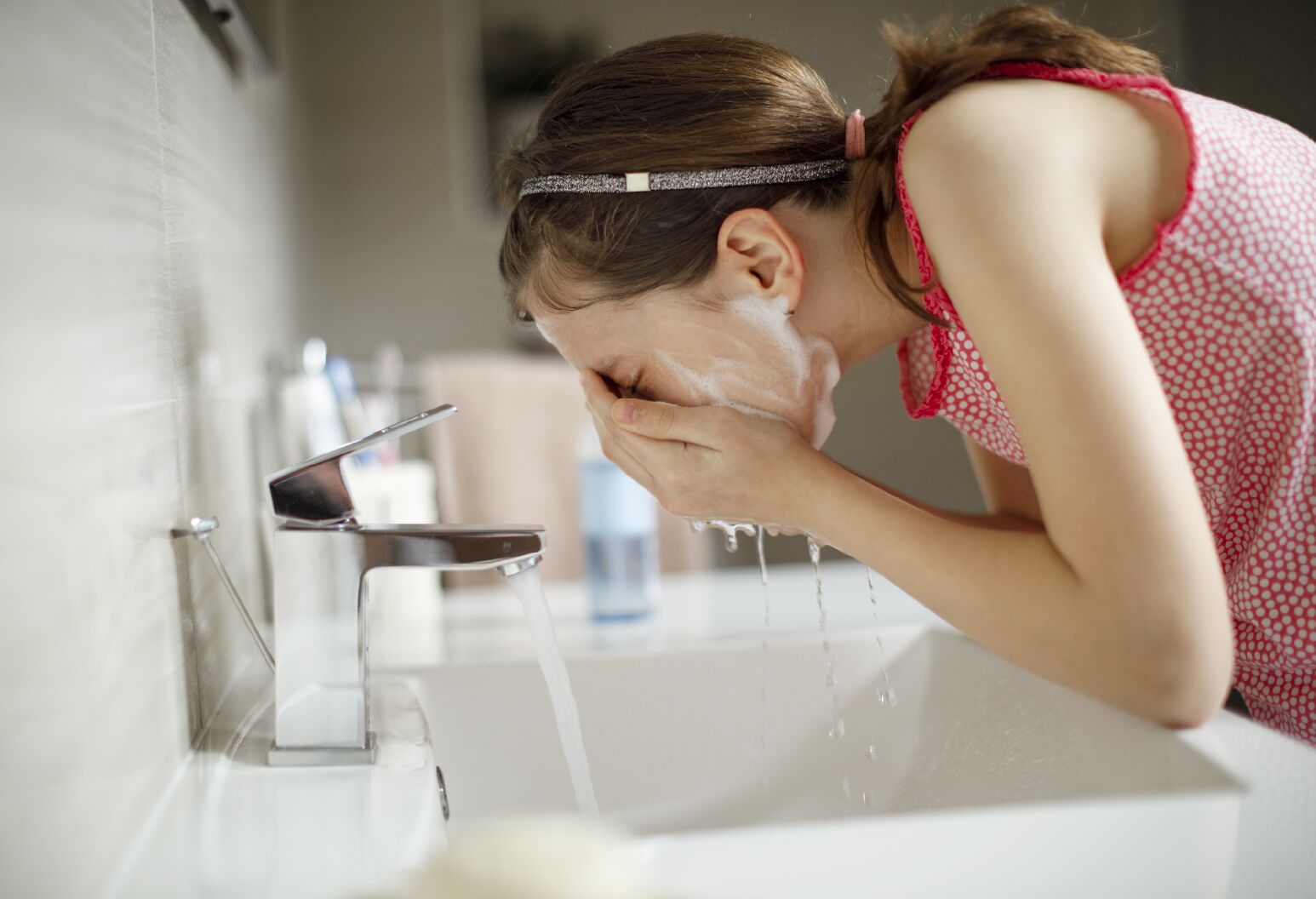 Young girl washes her face.