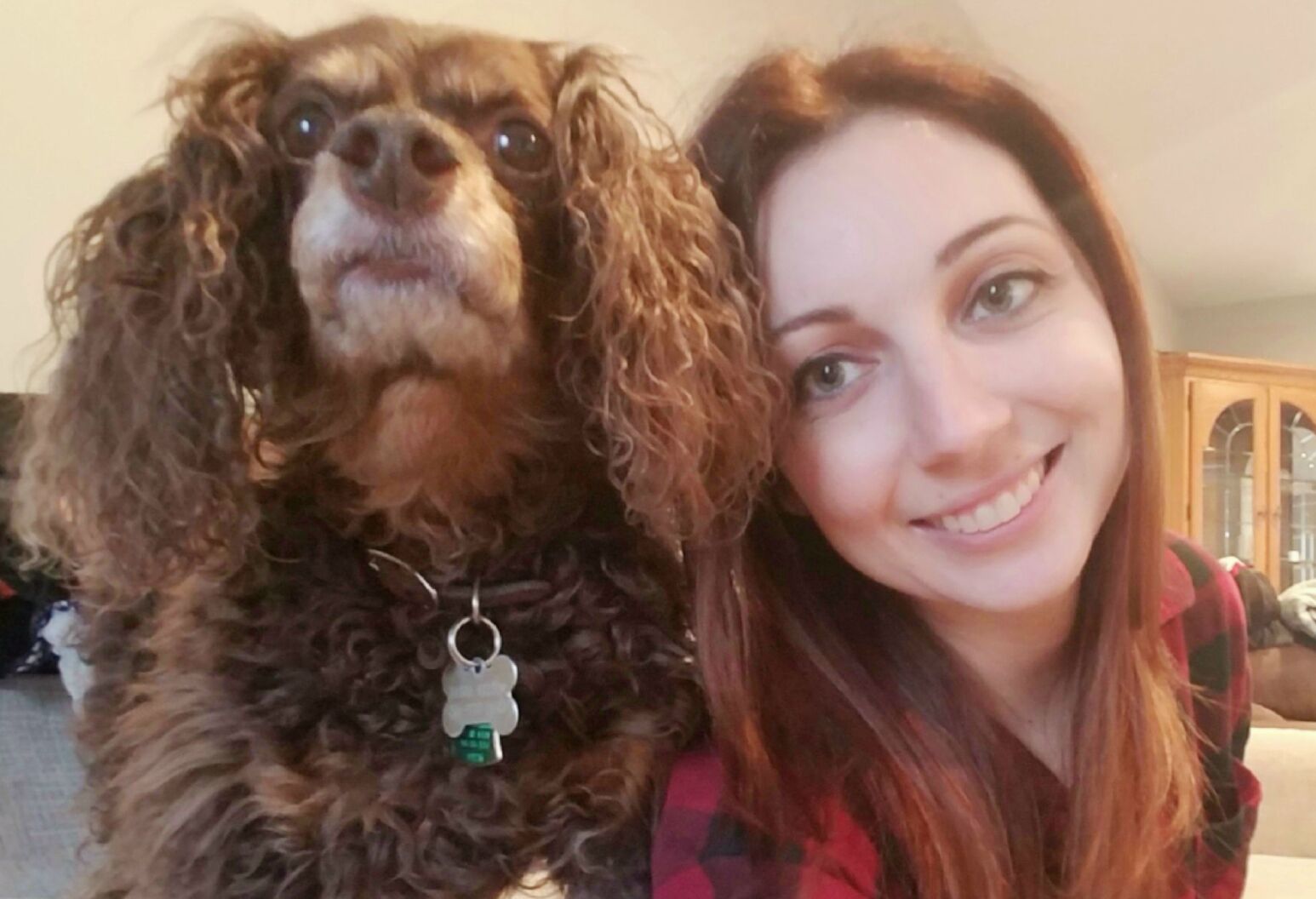 A woman smiles next to her dog.