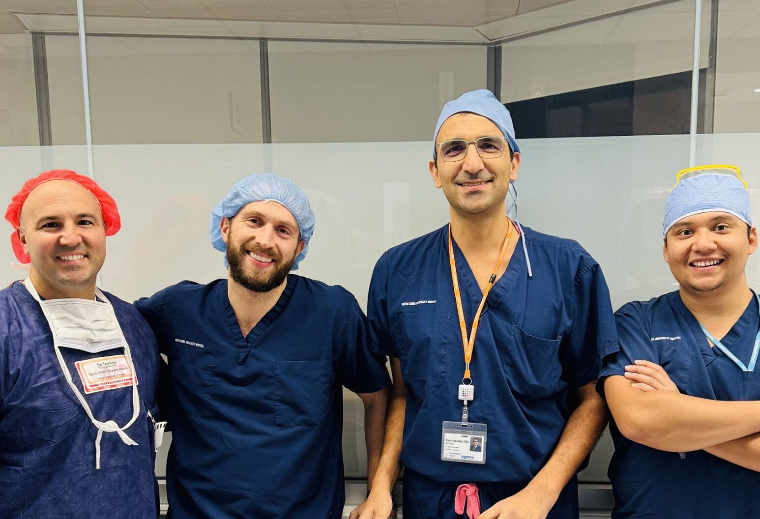 Several men in navy blue scrubs pose in a row for a photograph.