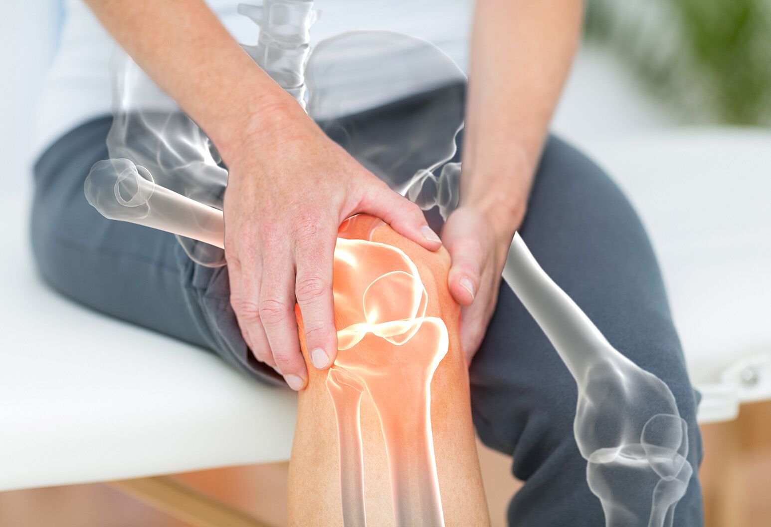 A person clutches a glowing knee. The person's bone structure is graphically overlaid over their legs.