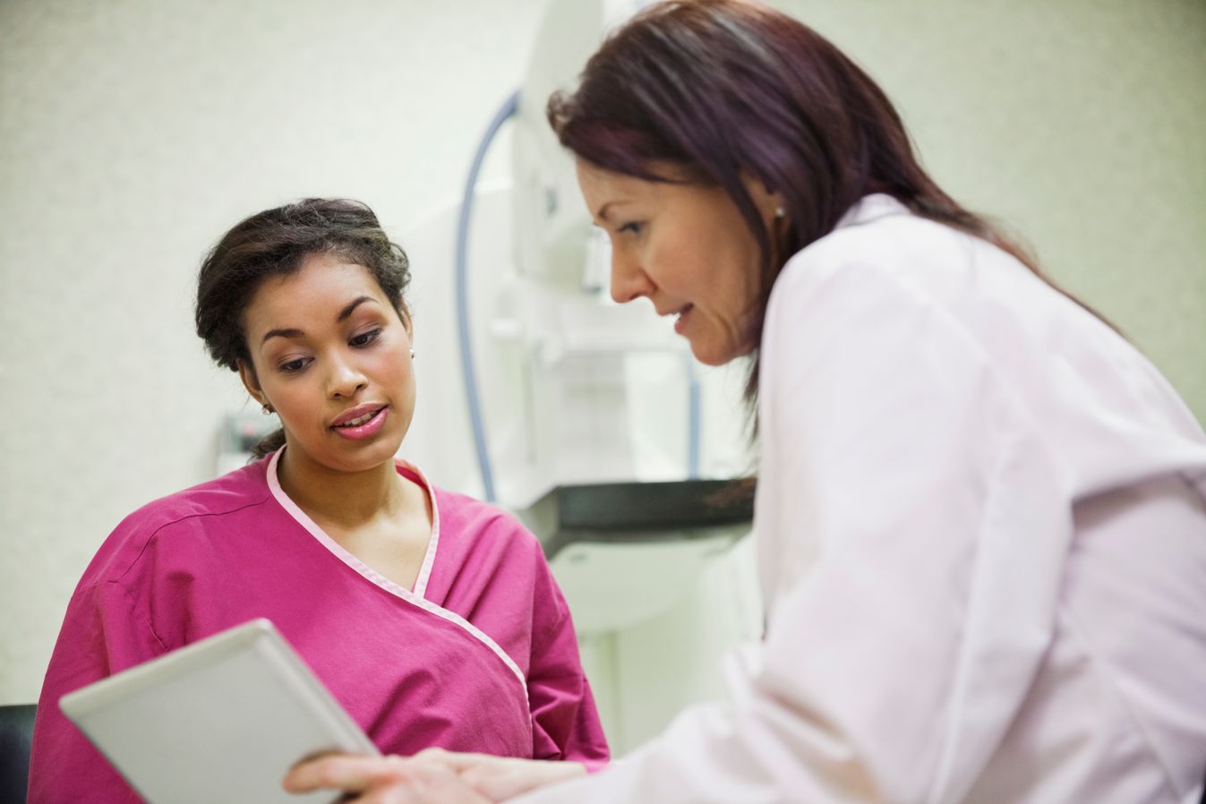 Patient in pink hospital gown talking to a doctor about her results