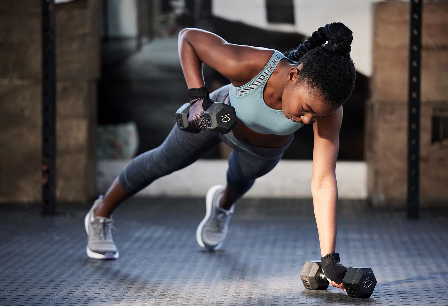 Gym workout, dumbbells and a black woman on the floor for fitness, exercise and training for sports. Strong, healthy and an African athlete with weights for strength, muscle and health at a club.