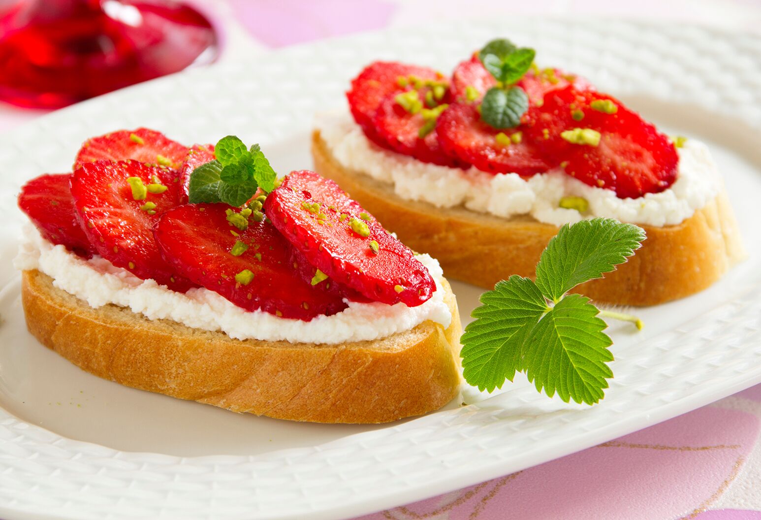 Bruschetta topped with ricotta, strawberries, and pistachio.