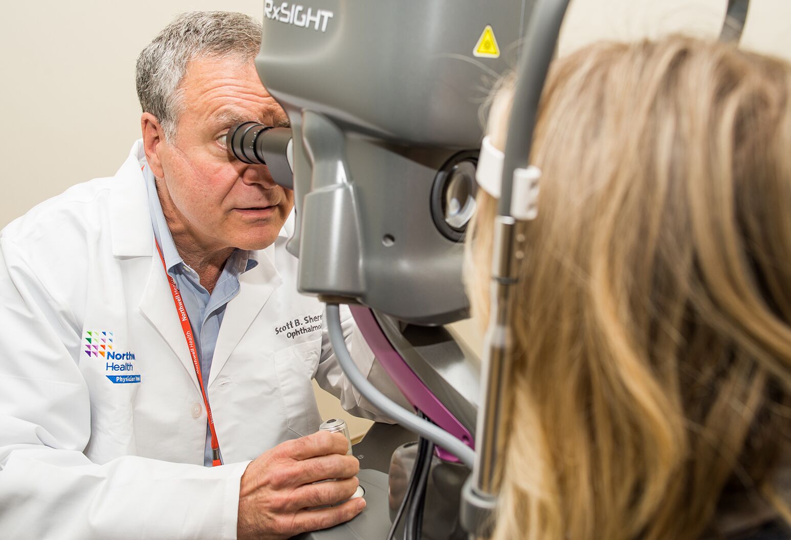 Scott Sheren, MD, director of ophthalmology at Northwell Health Eye Institute at Riverhead with the Light Delivery Device and a photo of the Light Adjustable Lens