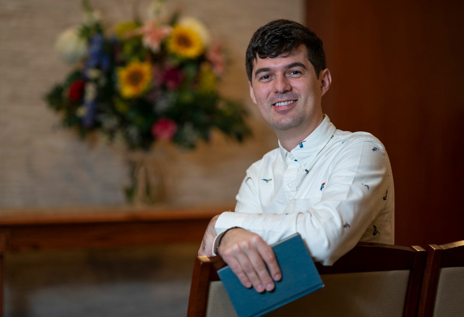 Man sitting in a chair smiling and holding a book