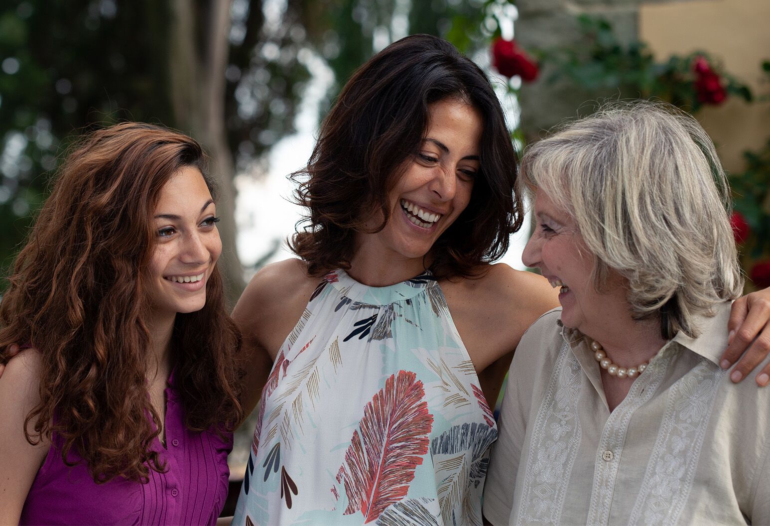 Three women of different age groups smiling while standing next to each other