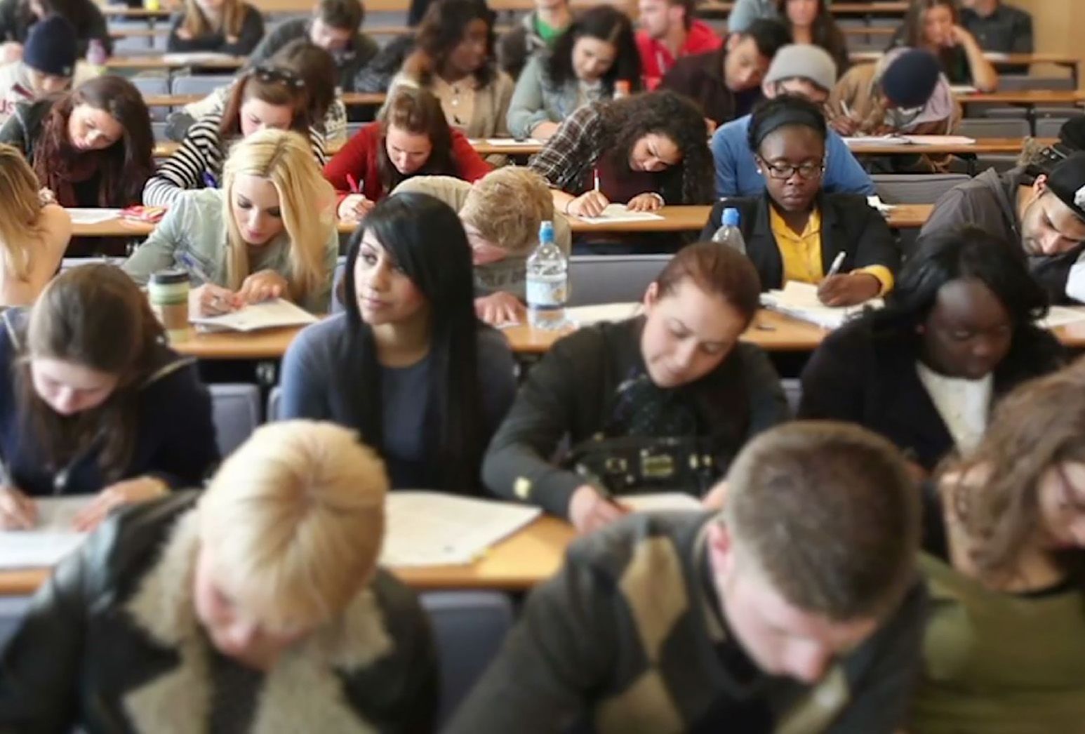 Classroom with a diverse group of students writing at their desks.