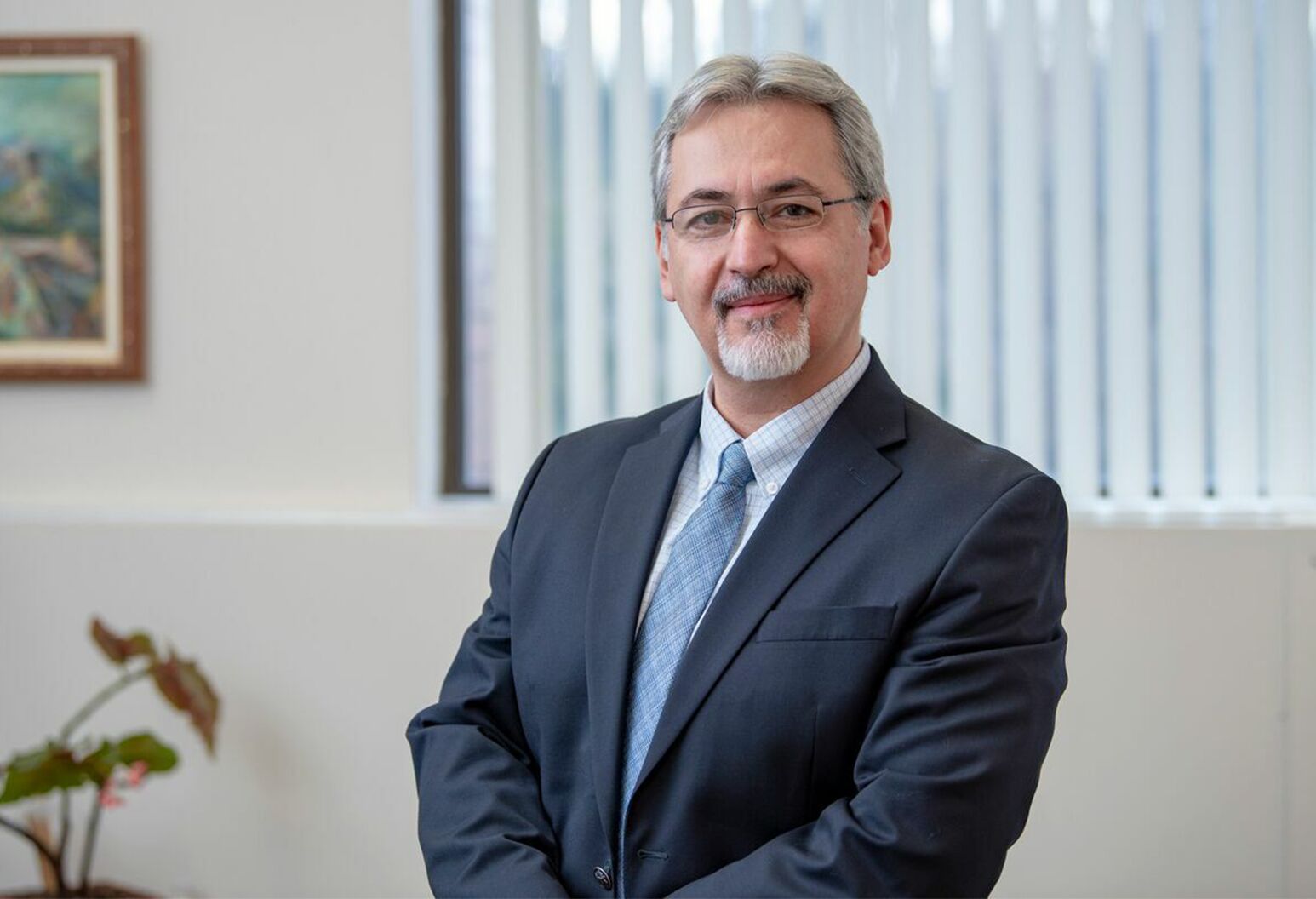 A man with gray hair and glasses poses in an office.