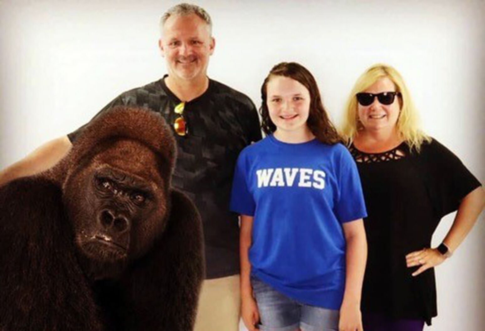 Jack, Bella and Robin D’Andrea stand smiling next to a superimposed image of a gorilla. 