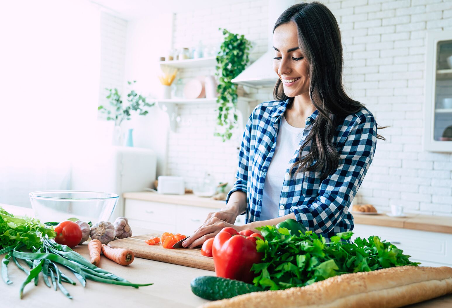 A woman cutting up vegetables in her kitchen.