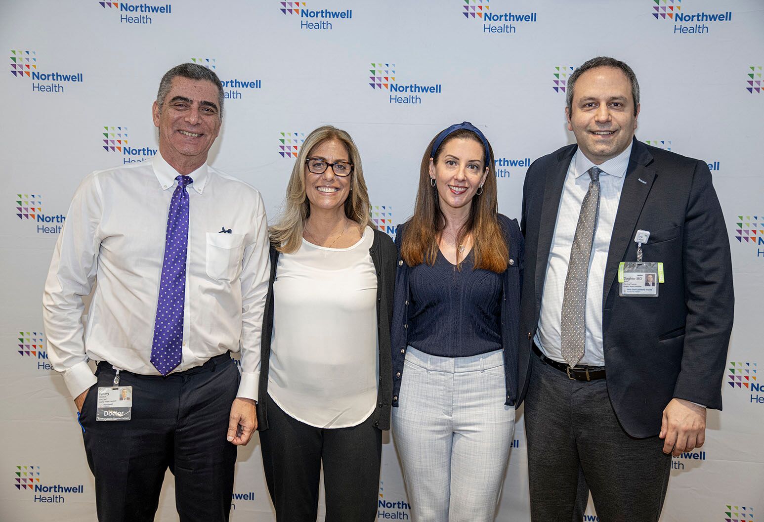 Two women and two men stand in a row against a Northwell backdrop and pose for a photograph.